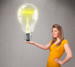 Photo: Beautiful lady holding realistic 3d light bulb Beautiful lady holding realistic 3d light bulb