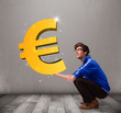 Good-looking boy holding a big 3d gold euro sign