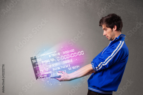 Photo: Casual man holding laptop with exploding data and numbers Casual man holding laptop with exploding data and numbers