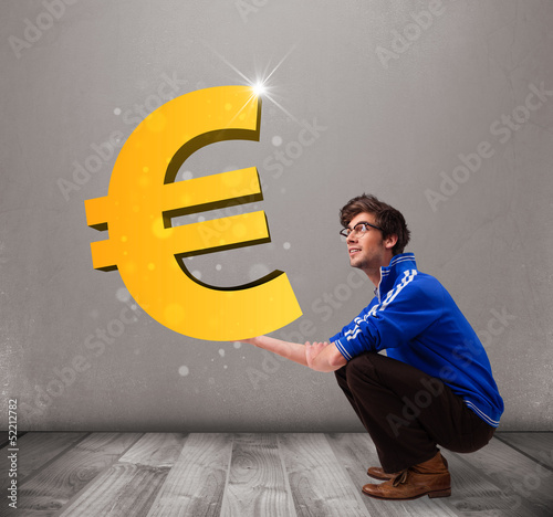 Photo: Good-looking boy holding a big 3d gold euro sign Good-looking boy holding a big 3d gold euro sign