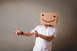 Young man gesturing with a cardboard box on his head with smiley