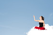 Foto: Young woman sitting on cloud with copy space Young woman sitting on cloud with copy space