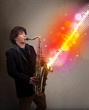 Young man playing on saxophone with colorful sound waves