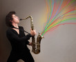 Attractive musician playing on saxophone while colorful abstract