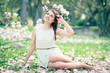Beautiful young woman sitting under a magnolia tree in bloom