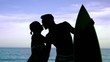 Man with surfboard kissing girlfriend on the beach