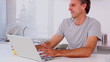 Mature man drinking orange juice while using his laptop