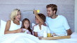 Family sitting in bed and having breakfast in bed