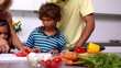 Mother showing her daughter how to chop vegetables with her family