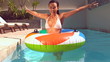 Happy woman emerging from underwater into rubber ring in pool