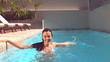 Happy woman standing and splashing in pool