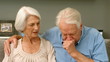 Old man coughing next to his wife