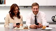 Couple showing each other their phones at breakfast