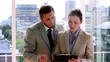 Business partners discussing notes on clipboard