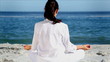 Brunette woman meditating in sukhasana pose rear view