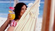 Pretty girl in a hammock raising her cocktail glass