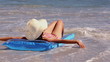 Girl sunbathing on a lilo on the beach getting splashed by the waves