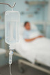 Close up of an intravenous drip next to a patient