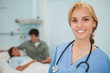 Blonde nurse smiling next to a patient