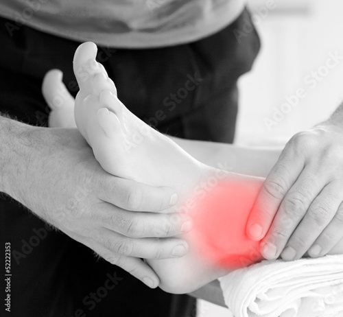 Photo: Physiotherapist working on patients highlighted ankle Physiotherapist working on patients highlighted ankle