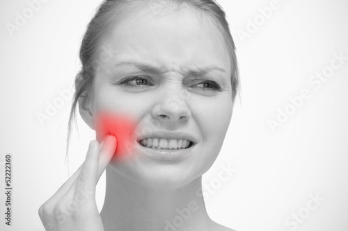 Photo: Woman touching red highlighted toothache Woman touching red highlighted toothache