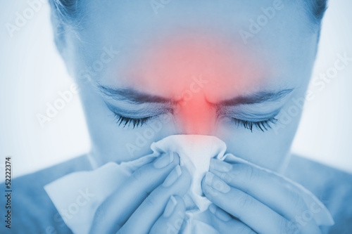 Photo: Woman blowing her nose with highlighted red sinus pain Woman blowing her nose with highlighted red sinus pain