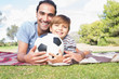 Portrait of happy father and son on picnic blanket with a football