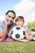 Portrait of father and son on picnic blanket with a football