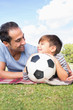 Happy father and son on picnic blanket with a football
