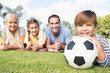 Portrait of son holding football with family behind him
