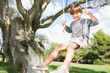 Cute boy on swing hanging from tree