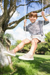 Happy boy on swing hanging from tree