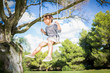 Cute boy swinging on swing hanging from tree