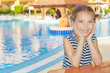 little girl in striped vest near resort's pool