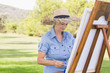 Woman in straw hat painting in the park