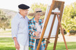Old couple wearing hats painting in the park