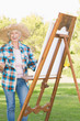 Foto: Smiling woman painting in the park Smiling woman painting in the park