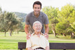 Portrait of elderly father with adult son standing with arms on shoulders
