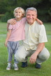 Portrait of grandfather crouching beside grandson