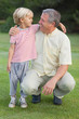 Grandfather crouching beside grandson looking at each other