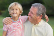 Grandfather smiling at grandson with arm over his shoulder
