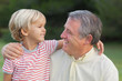 Grandson smiling at grandfather with arm over his shoulder