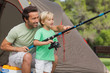 Father showing his son how to fish at camping site