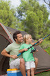 Father showing his son how to fish on camping holiday