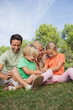 Happy family sitting on picnic blanket and messing together