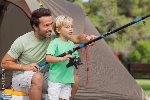 Photo: Father showing his son how to fish at camping site Father showing his son how to fish at camping site