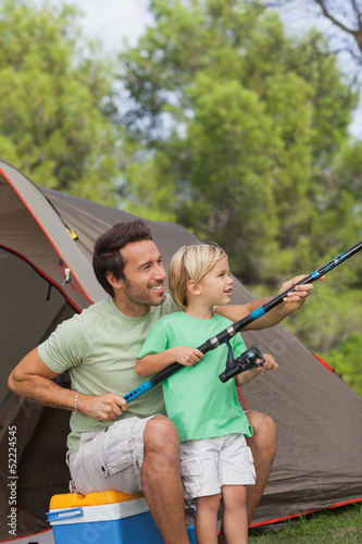 Photo: Father showing his son how to fish on camping holiday Father showing his son how to fish on camping holiday