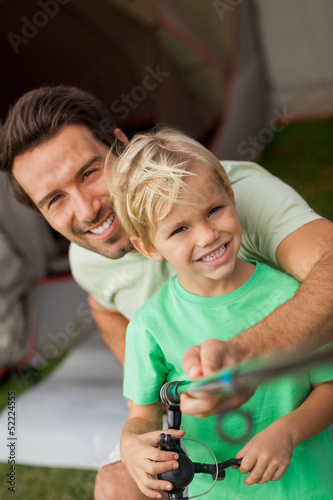 Photo: Portrait of father showing young son how to fish Portrait of father showing young son how to fish
