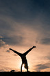Little girl cartwheeling at sunset