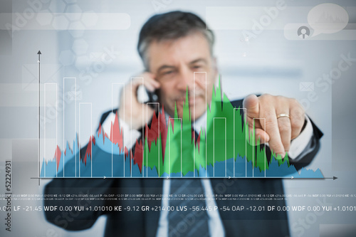 Photo: Businessman selecting point on large graph on touchscreen Businessman selecting point on large graph on touchscreen